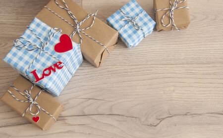Valentine's day background. Cute composition with handmade gift boxes and red hearts on wooden...