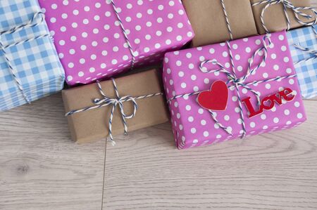 Valentine's day background. Cute composition with handmade gift boxes and red hearts on wooden...