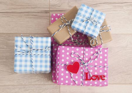 Valentine's day background. Cute composition with handmade gift boxes and red hearts on wooden...