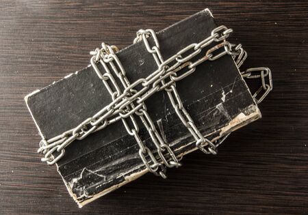Old book with chain on dark wood background