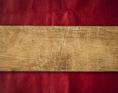 Wooden blank plank with red  leather background. Top view. Copy space