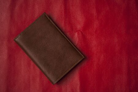 brown leather wallet on red background. Flat lay, top view, copy space. 