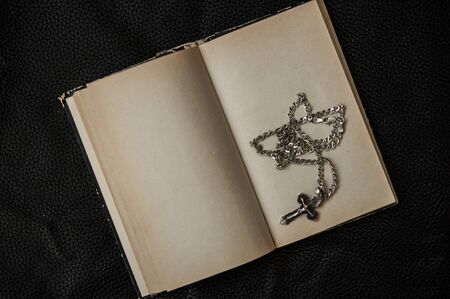 Closeup of Christian cross with silver chain on blank open book