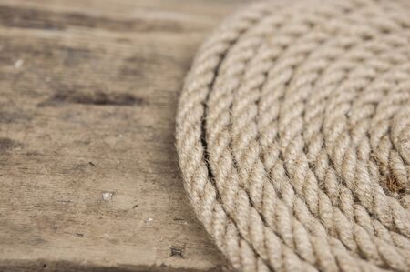 Close-up of a thick hemp rope. Natural rope on an old wooden table. Side view. Soft focus. 