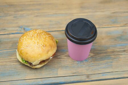Unhealthy food: a hamburger and coffee in a paper cup on old wooden backgroundの写真素材