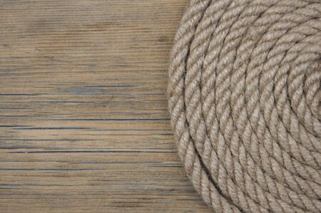Close-up of a thick hemp rope. Natural rope on an old wooden table. Side view. Soft focus.の写真素材