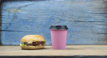 Unhealthy food: a hamburger and coffee in a paper cup on old wooden backgroundの写真素材