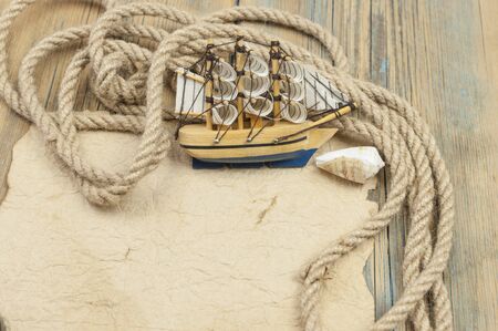 old paper, rope and model classic boat on wood background 
