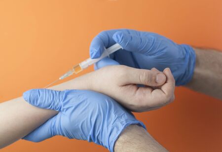 Vaccination concept. Doctor in blue gloves gives an injection. baby, hand is almost ready for an injectionの写真素材