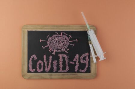 Pandemic concept "covid-19", a virus written in chalk on a chalkboardの写真素材