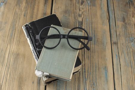 Closed old vintage books and glasses on a wooden table. Top viewの写真素材