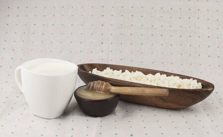 Cottage cheese with honey in a clay bowl on polka dot background, top view