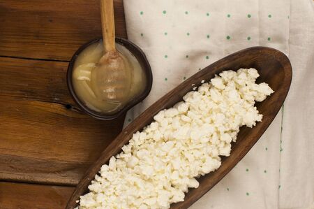 Cottage cheese with honey in a clay bowl on wooden background, top viewの写真素材