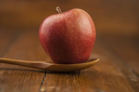 red apple on wood spoonの写真素材