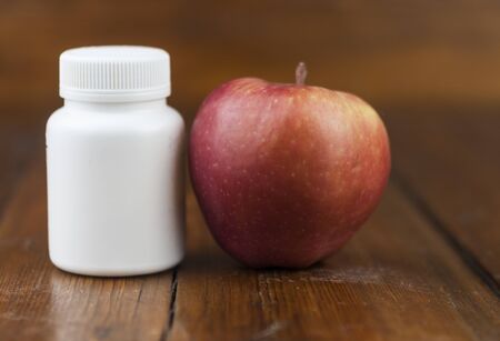 apple and medical tablets on wood tableの写真素材