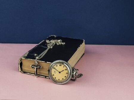 Vintage pocket watch with the cross on old book