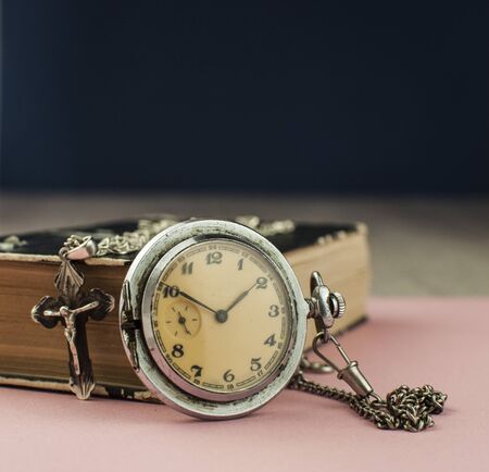 Vintage pocket watch with the cross on old bookの写真素材