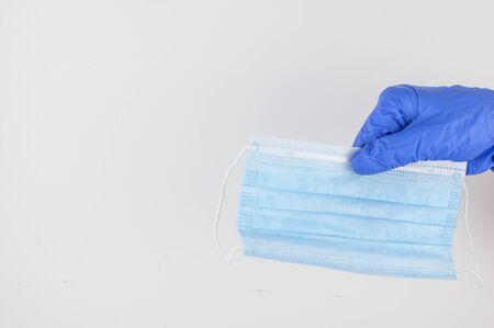 hand holds a medical face mask against viruses and bacteria on a white background, protective...