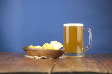 Beer glass with beer and smoked fish close-up. Beer mug with beer and potato chips, crackers on a wood background and copy space.の写真素材