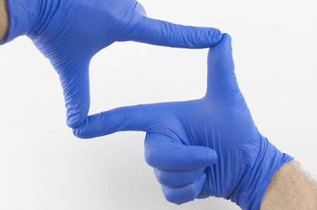 Cropped close-up image of a human hand wearing blue surgical gloves.の写真素材