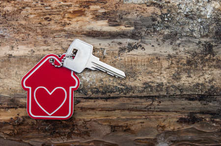 House key on a house shaped keychain resting on wooden floorboards concept for real estate, moving...
