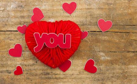red heart made of yarn against the wall of wood