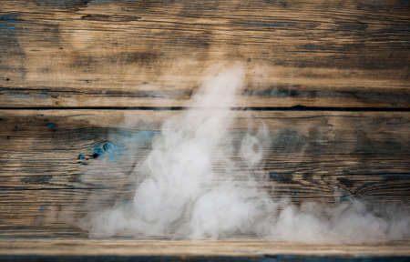 empty wooden table with smoke float up on dark backgroundの写真素材