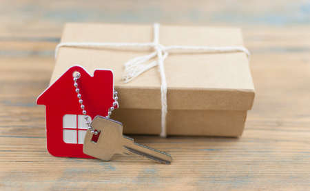 Keychain house and keys in gift box on wooden background. Real estateの写真素材