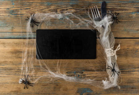 Halloween table setting with blank blackboard on old rustic wooden table holiday card template copy space. Menu cardの写真素材