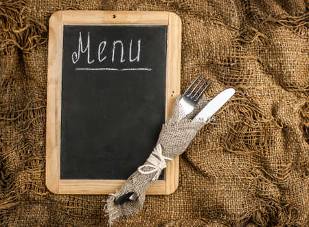 Restaurant menu. Top view of chalkboard menu laying on very old burlap background