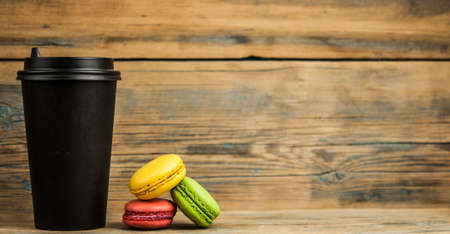 macaroons and disposable coffee cup on wooden rustic table