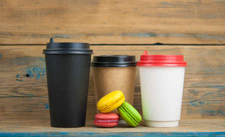 macaroons and disposable coffee cup on wooden rustic table