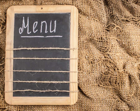Restaurant menu. Top view of chalkboard menu laying on very old burlap background