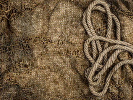 Hemp rope on burlap. Close-up of a natural rope and fabric. Calm nice background.の写真素材