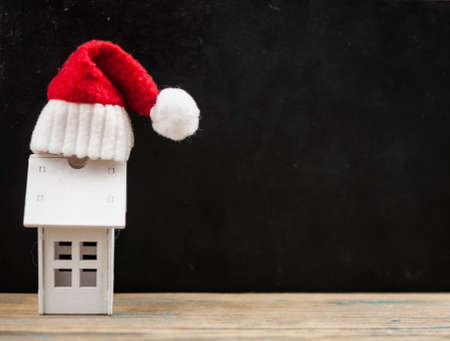 Santa hat with miniature house model on wooden tableの写真素材