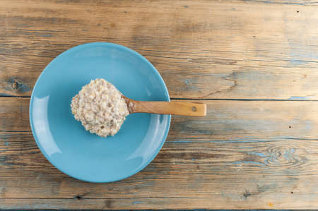 Healthy food classic porridge in blue dish on wood background. oatmeal food breakfast. Top view.の写真素材