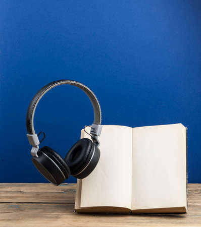Headphones with book hover in the air. On a dark blue background.の写真素材