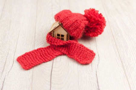 House model with knitted hat and scarf on table wooden background. Heating conceptの写真素材