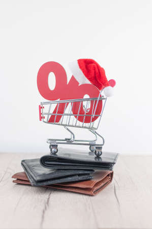 Shopping cart from the supermarket and sign percent with Santa hat on white background. Shopping in the Mall, shop, shopping, a large selection.の写真素材