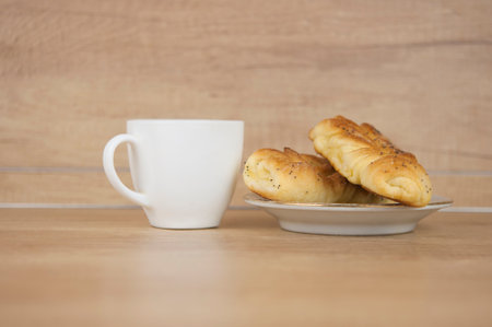 Two bun with poppy seeds with coffee cup on wood table. Breakfast. Good Morning. Coffee timeの写真素材