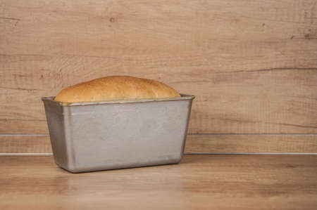 Homemade toasted whole wheat bread and metal form for bread on wood tableの写真素材