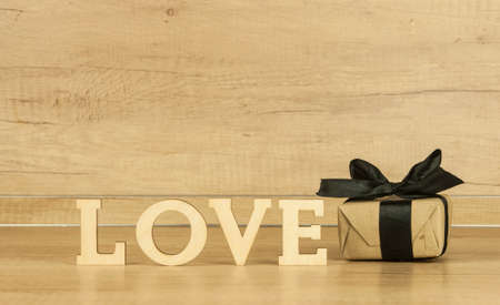 word Love from wooden letters with gift box on a wood background. Happy valentines dayの写真素材