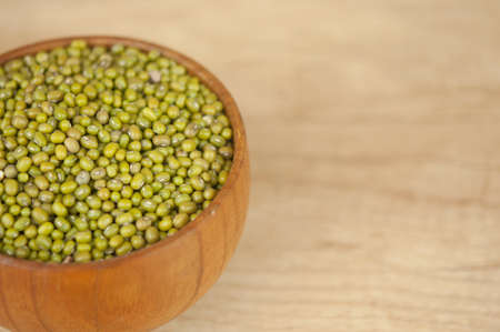 Mung bean, green moong dal in wooden bowl. Copy space. Wooden background.