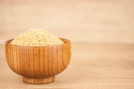 wheat groats in a wooden bowl on a wooden table backgroundの写真素材