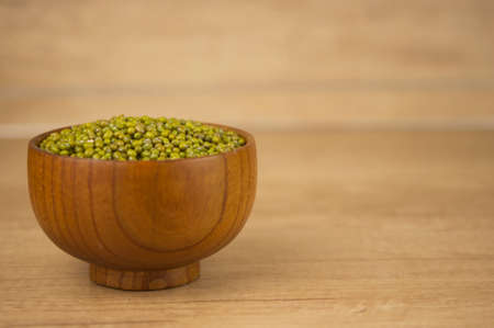 Mung bean, green moong dal in wooden bowl. Copy space. Wooden background.の写真素材