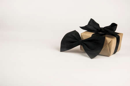One gift box wrapped in craft paper with butterfly tie on white background. Concept Father's Day or Birthday background. International men's day concept.の写真素材
