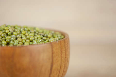 Mung bean, green moong dal in wooden bowl. Copy space. Wooden background.の写真素材