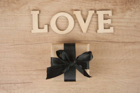 word Love from wooden letters with gift box on a wood background. Happy valentines dayの写真素材