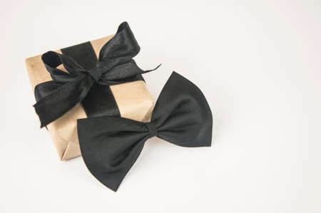 One gift box wrapped in craft paper with butterfly tie on white background. Concept Father's Day or Birthday background. International men's day concept.の写真素材