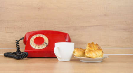 Two bun with poppy seeds with coffee cup and retro rotary phone on wood table. Breakfast. Coffee timeの写真素材
